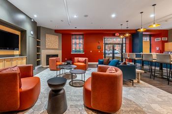 A room with orange chairs and a television on the wall